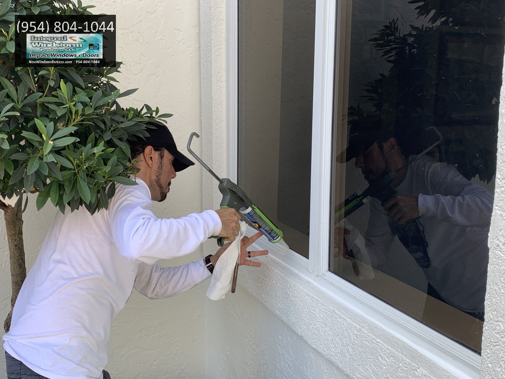 Window caulking service company that is repairing window leaks by applying new caulking around the windows.